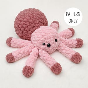 Puede incluir: Un pulpo de ganchillo rosa y malva hecho a mano con ojos de seguridad negros y una bola malva a juego. El pulpo tiene ocho tentáculos y una cabeza redonda. El texto "PATTERN ONLY" está en un círculo blanco.