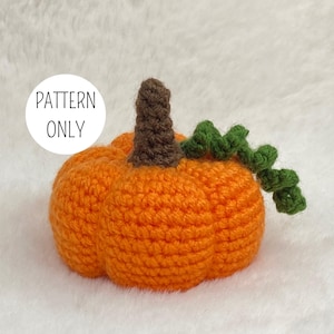 May include: A crocheted orange pumpkin with a brown stem and green vine. The pumpkin is handmade and has a textured appearance. The text "PATTERN ONLY" is in a white circle on the left side. Ideal for autumn decorations.