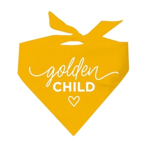 May include: A mustard yellow pet bandana with the words "golden CHILD" in white script and block letters, along with a white heart symbol. The bandana is tied at the top, creating a triangular shape.