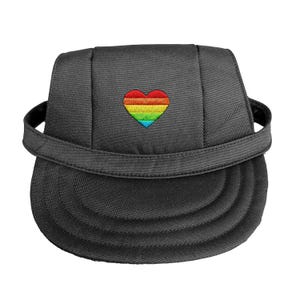 May include: A dark gray baseball cap featuring a rainbow heart embroidered on the front. The cap has a curved brim and an adjustable strap. The rainbow heart design includes red, orange, yellow, green, blue, and purple.