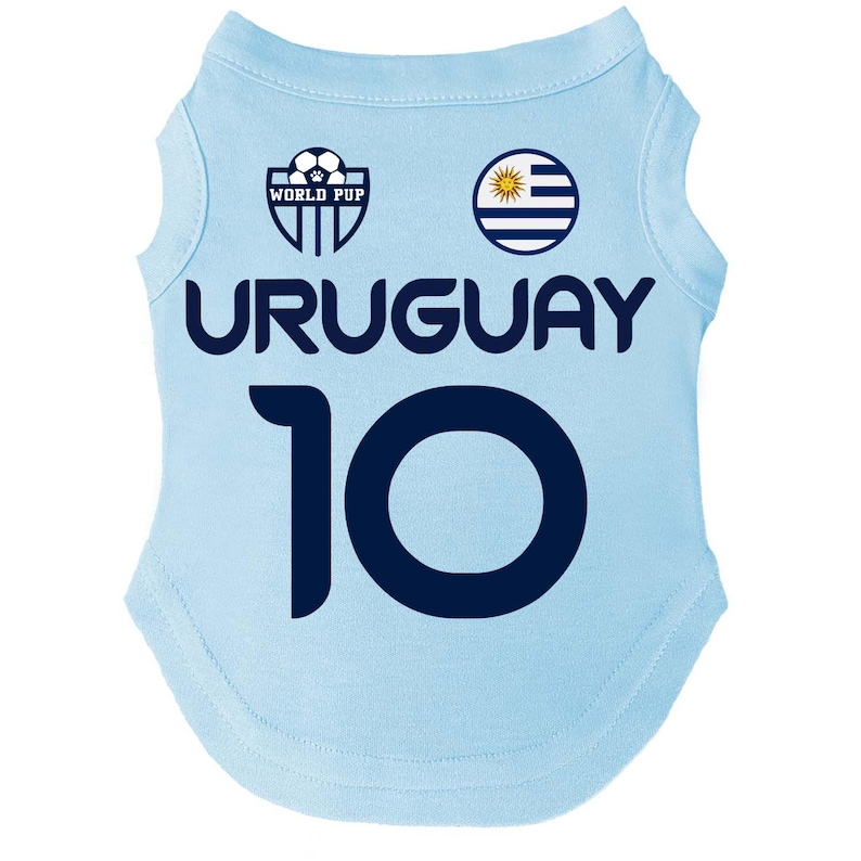 Puede incluir: Camiseta azul claro para perros con la palabra "URUGUAY" en azul marino y el n&uacute;mero "10". La camiseta presenta un logotipo de "WORLD PUP" y la bandera uruguaya. Un art&iacute;culo deportivo para mascotas.
