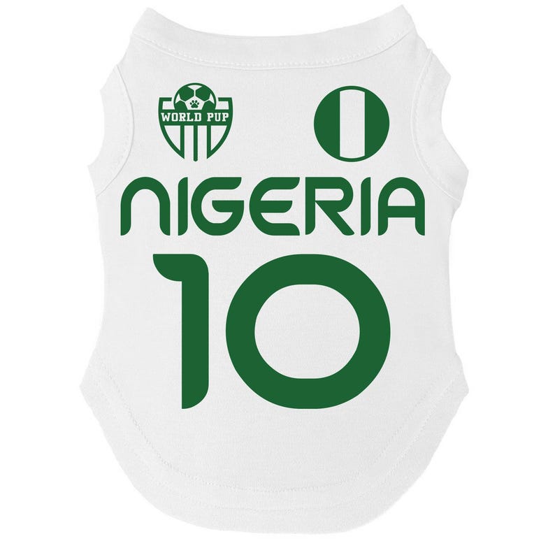 Puede incluir: Camiseta blanca para mascotas con texto y gr&aacute;ficos verdes. La camiseta muestra la palabra "NIGERIA" y el n&uacute;mero "10" en verde. Tambi&eacute;n se ve un c&iacute;rculo verde y un logotipo que dice "WORLD PUP".