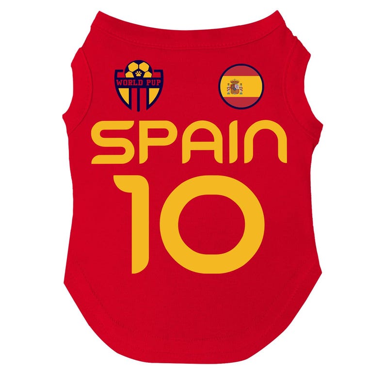 Puede incluir: Camiseta roja para perro con la palabra "SPAIN" en letras amarillas y el n&uacute;mero "10". La camiseta tiene un parche circular con la bandera espa&ntilde;ola y un logotipo "WORLD PUP" con un bal&oacute;n de f&uacute;tbol.