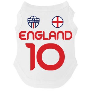 Puede incluir: Camiseta blanca para perro con la palabra "ENGLAND" en letras rojas y el n&uacute;mero "10". La camiseta tiene un escudo azul y blanco que dice "WORLD PUP" y una cruz roja sobre un c&iacute;rculo blanco.