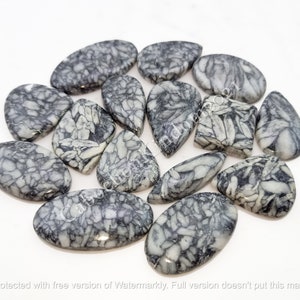 Peut inclure: Une collection de 14 cabochons en pierre naturelle de formes et de tailles variées. Les pierres sont de couleur gris clair avec des veines et des motifs noirs.