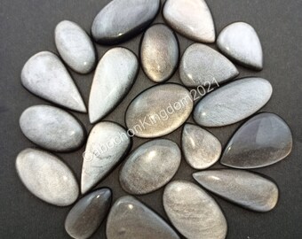 Könnte beinhalten: Eine Sammlung von 17 silbernen und schwarzen Edelstein-Cabochons in verschiedenen Formen und Größen. Die Steine haben eine schimmernde, irisierende Oberfläche.