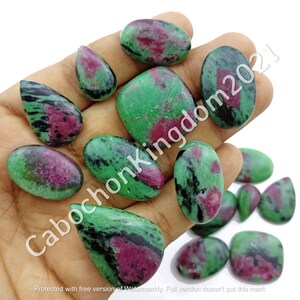 Könnte beinhalten: Eine Sammlung von grünen, schwarzen und rosafarbenen Edelstein-Cabochons. Die Cabochons haben verschiedene Formen und Größen, darunter ovale, tropfenförmige und quadratische.