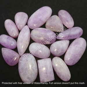 May include: A collection of polished, lavender-colored gemstones in various shapes, including ovals, teardrops, and rectangles. The stones have a smooth, glossy surface and are arranged on a dark background. The text "CabochonKingdom2021" is visible.
