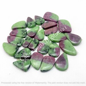 May include: A collection of polished ruby zoisite gemstones in various shapes, including teardrops and ovals. The stones feature a mix of green and deep red hues, with a smooth, glossy finish. These gemstones are ideal for jewelry making.