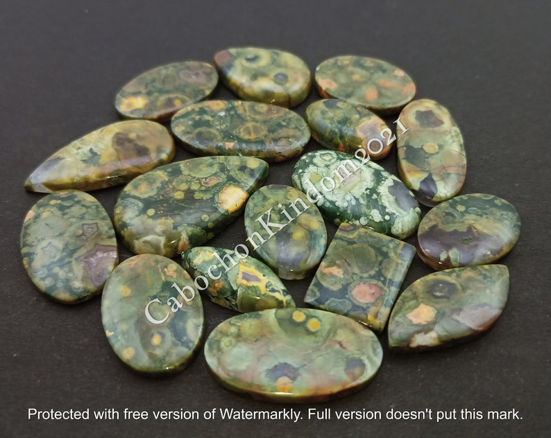 May include: A collection of 18 green, brown, and orange polished ocean jasper cabochons. The cabochons are various shapes and sizes, with a speckled pattern.