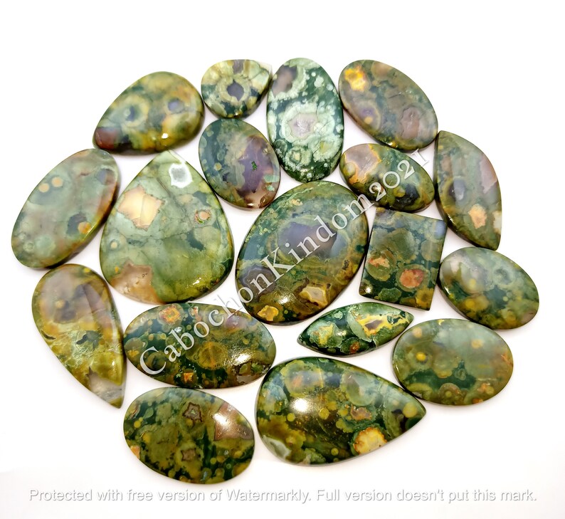 May include: A collection of 15 green, brown, and white ocean jasper cabochons. The cabochons are various shapes and sizes, including oval, teardrop, and rectangular.