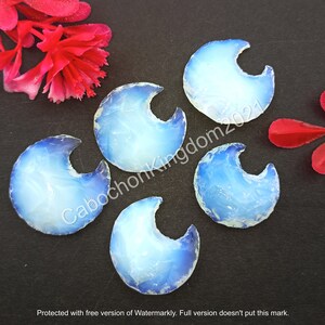 Può includere: Cinque cabochon di opale blu e bianco a forma di mezzaluna. I cabochon sono lisci e lucidi, con un leggero bagliore iridescente.