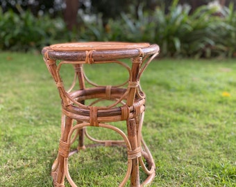 Peut inclure: Un tabouret rond en osier brun avec un motif tissé. Le tabouret est posé sur une pelouse verte.