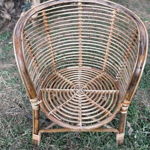 K&ouml;nnte beinhalten: Ein geflochtener Rattanstuhl mit einem runden Sitz und einer abgerundeten R&uuml;ckenlehne. Der Stuhl ist aus nat&uuml;rlichem braunem Rattan gefertigt und hat ein schlichtes, elegantes Design.