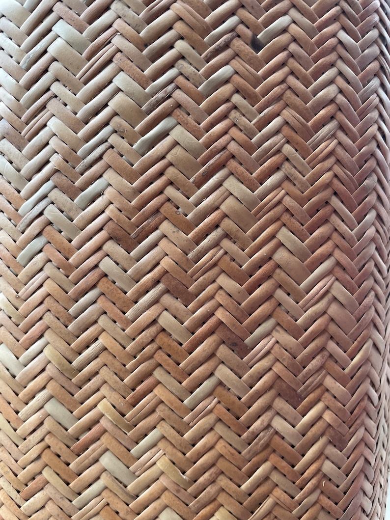 May include: Close-up of a woven basket made from natural materials. The basket has a herringbone pattern and is a light brown colour.
