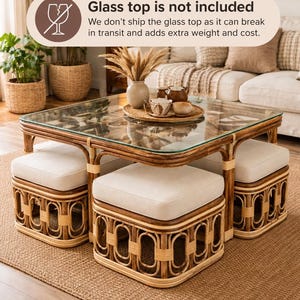 May include: A square rattan coffee table with four matching square ottomans featuring cream-colored upholstered cushions. The table frame is made of bent rattan poles. Text on the image states: Glass top is not included.