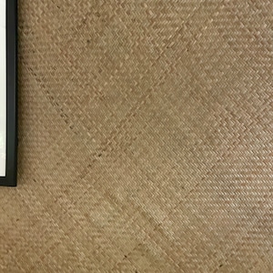 May include: A close-up of a woven wall covering made of natural materials. The woven pattern is a diagonal weave with a light brown colour.