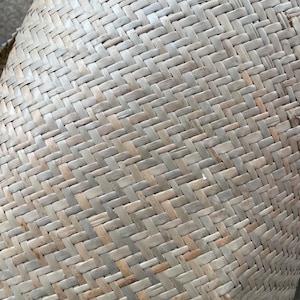 May include: Close-up of a woven basket made from natural materials. The basket is light brown in colour and has a tightly woven pattern.