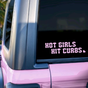 May include: Pink Jeep with a black rear window and a pink vinyl sticker that reads "HOT GIRLS HIT CURBS."
