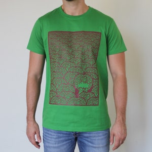 Könnte beinhalten: Ein grünes T-Shirt mit einem kastanienbraunen Grafikdruck eines Gesichts, umgeben von einem Muster aus Wirbeln.