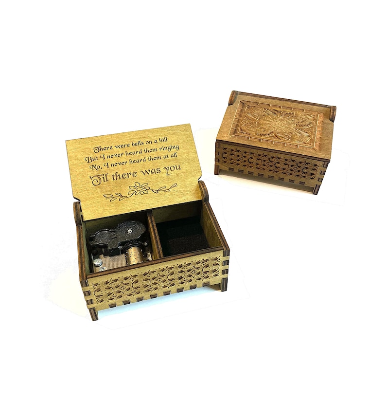 Puede incluir: Una caja de m&uacute;sica de madera con un dise&ntilde;o grabado y una cita que dice "There were bells on a hill But I never heard them ringing No, I never heard them at all Til there was you".