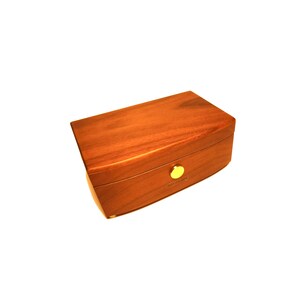 Puede incluir: Una caja de madera con una tapa curva y un cierre dorado. La caja est&aacute; hecha de madera oscura con un acabado liso.