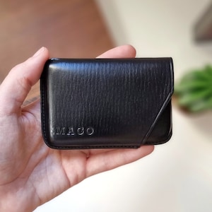 Custom black leather card holder with initials MAGO and minimalist design.