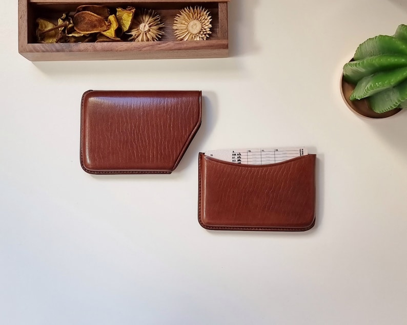 brown colored leather card holder shown on a table and open. This card holder opens by pulling the case to one side.