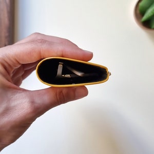 leather eyeglass case held in one hand, viewed from above so you can see the inside of the glasses case