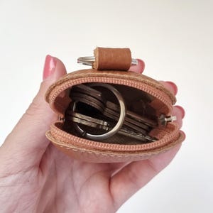 Open AirPods leather case with zipper, shown held in hand