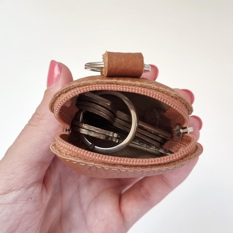 Open AirPods leather case with zipper, shown held in hand
