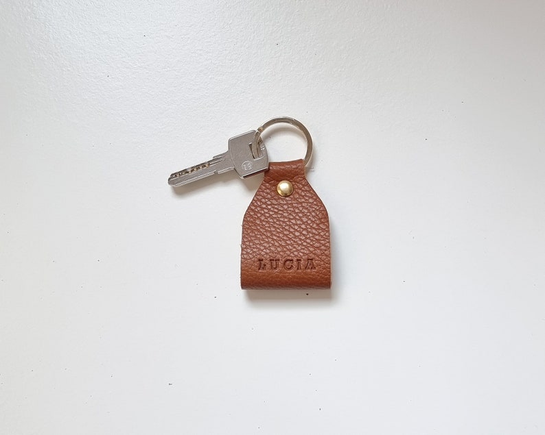 Small leather keychain engraved with five initials (name of Lucia). Brown color, full grain leather.