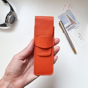 pen sleeve pouch in bright orange. This pen sleeve pouch is made of full grain leather that feels very soft to the touch.