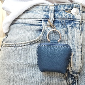 Blue leather AirPods case clipped on jeans belt loop as practical purse charm
