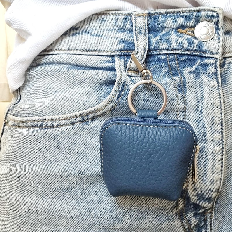 Blue leather AirPods case clipped on jeans belt loop as practical purse charm