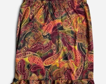 May include: A knee-length skirt featuring a vibrant paisley pattern in shades of deep burgundy, mustard yellow, olive green, and burnt orange. The garment has an elasticized waistband and a ruffled hemline along the bottom edge of the fabric.