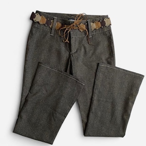 May include: Dark gray flared pants with a decorative belt. The belt is made of brown and tan leather pieces and a brown tie. The pants have white stitching and a subtle shimmer.