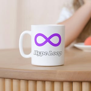 Könnte beinhalten: Weiße Keramiktasse mit einem lila Unendlichkeitszeichen und dem Text "Hype Loop" in Schwarz.