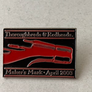May include: A rectangular pin with a black background and a red horse head design. The pin reads "Thoroughbreds & Redheads" and "Maker's Mark • April 2003" in silver lettering. The pin has a silver border.