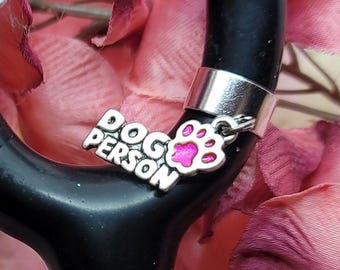 May include: A silver stethoscope charm with a pink paw print and the words "DOG PERSON" in silver lettering.