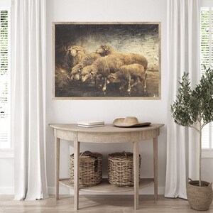 May include: A vintage-style print of a group of sheep gathered together in a field. The print is framed in a rustic wood frame and has a distressed, aged look.