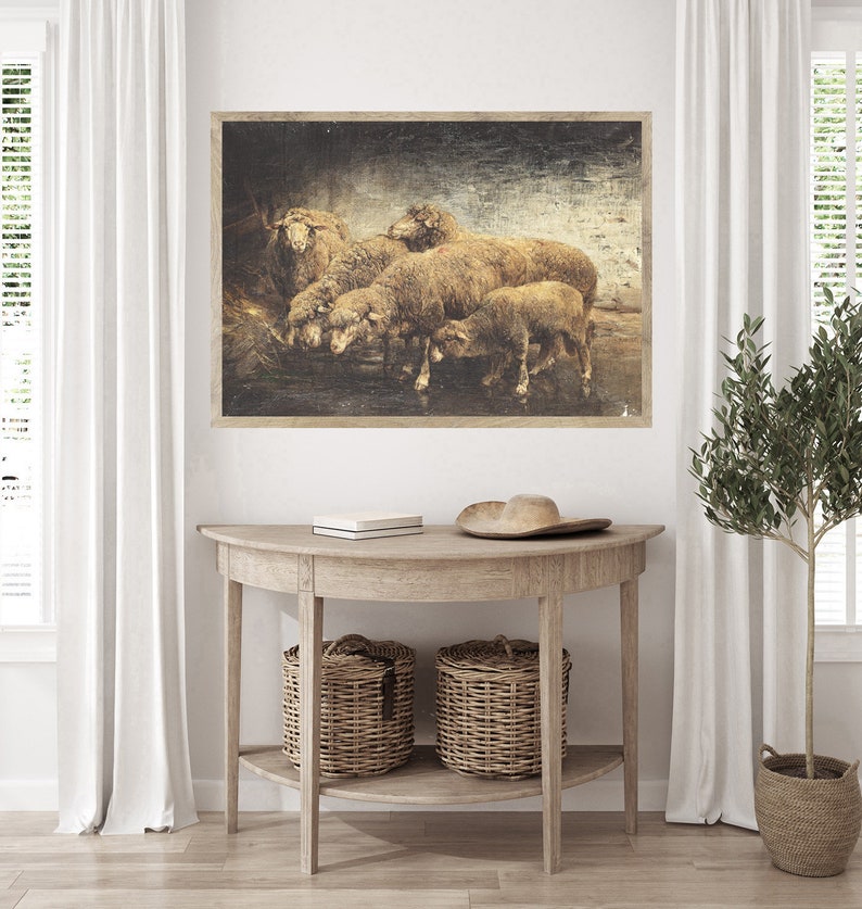 May include: A vintage-style print of a group of sheep gathered together in a field. The print is framed in a rustic wood frame and has a distressed, aged look.