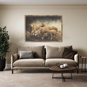 May include: A framed sepia-toned print of a group of sheep standing in a field. The sheep are brown and white and have fluffy wool. The print is set against a beige wall above a brown couch.