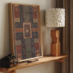 May include: A framed rectangular wall art piece featuring a vertical pattern of red, blue, and green geometric and floral motifs. Beside it sits a lamp with a white textured pebble-like shade on a blocky wooden base and a vintage black camera.