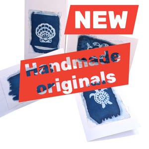 May include: Handmade originals greeting cards with a blue and white design. The cards feature a seashell, turtle, and other sea-themed images. The word "NEW" is in a red banner.