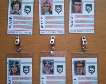 May include: Six plastic ID badges with photos of characters from the TV show Thunderbirds. Each badge has the text "W.A.S.P." and "WORLD SECURITY PATROL" along with the character's name, rank, and the vehicle they are assigned to.