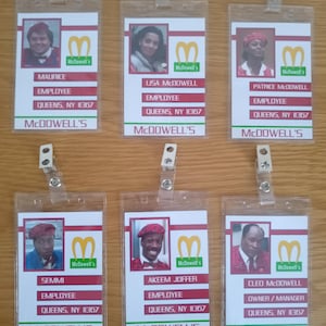 Könnte beinhalten: Sechs Mitarbeiterausweise von McDowell's mit Fotos, Namen und Berufsbezeichnungen. Die Ausweise haben ein rot-weißes Design mit dem McDowell's-Logo und dem Text "Queens, NY 11367". Die Ausweise befinden sich in transparenten Kunststoffhaltern.