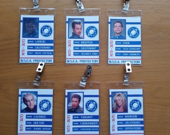 May include: Six blue and white plastic ID badges with a picture of a person, their name, rank, and post. The badges are labeled "N.S.E.A. PROTECTOR" and "NTE-3120".