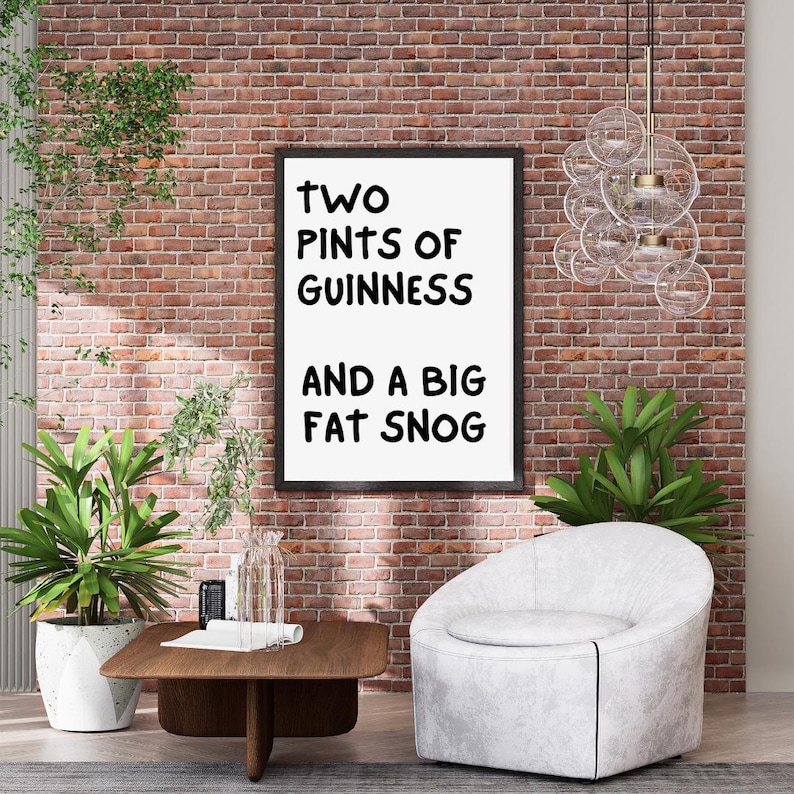 May include: A black framed print with white text that reads "two pints of Guinness and a big fat snog" hanging on a brick wall. A white armchair sits in front of the print, and a wooden coffee table sits in front of the chair.
