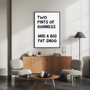 May include: A black and white framed print with the text "TWO PINTS OF GUINNESS AND A BIG FAT SNOG" hanging on a white wall above a wooden cabinet with two chairs and a coffee table.